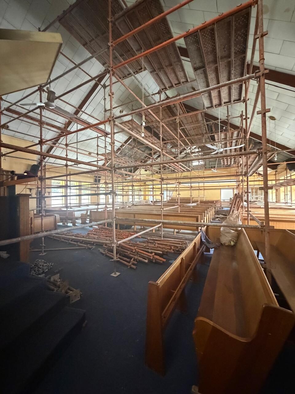 Access scaffolding erected across the full width of the sanctuary, spanning above the pews